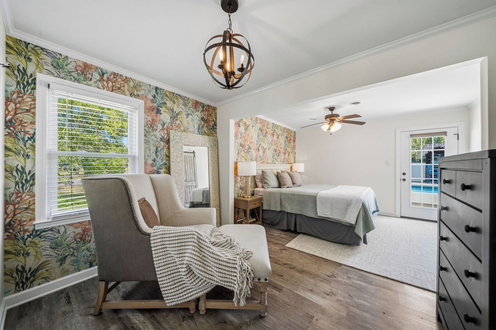 A bedroom with a bed, a chair, a dresser, a ceiling fan, and a window with blinds.
