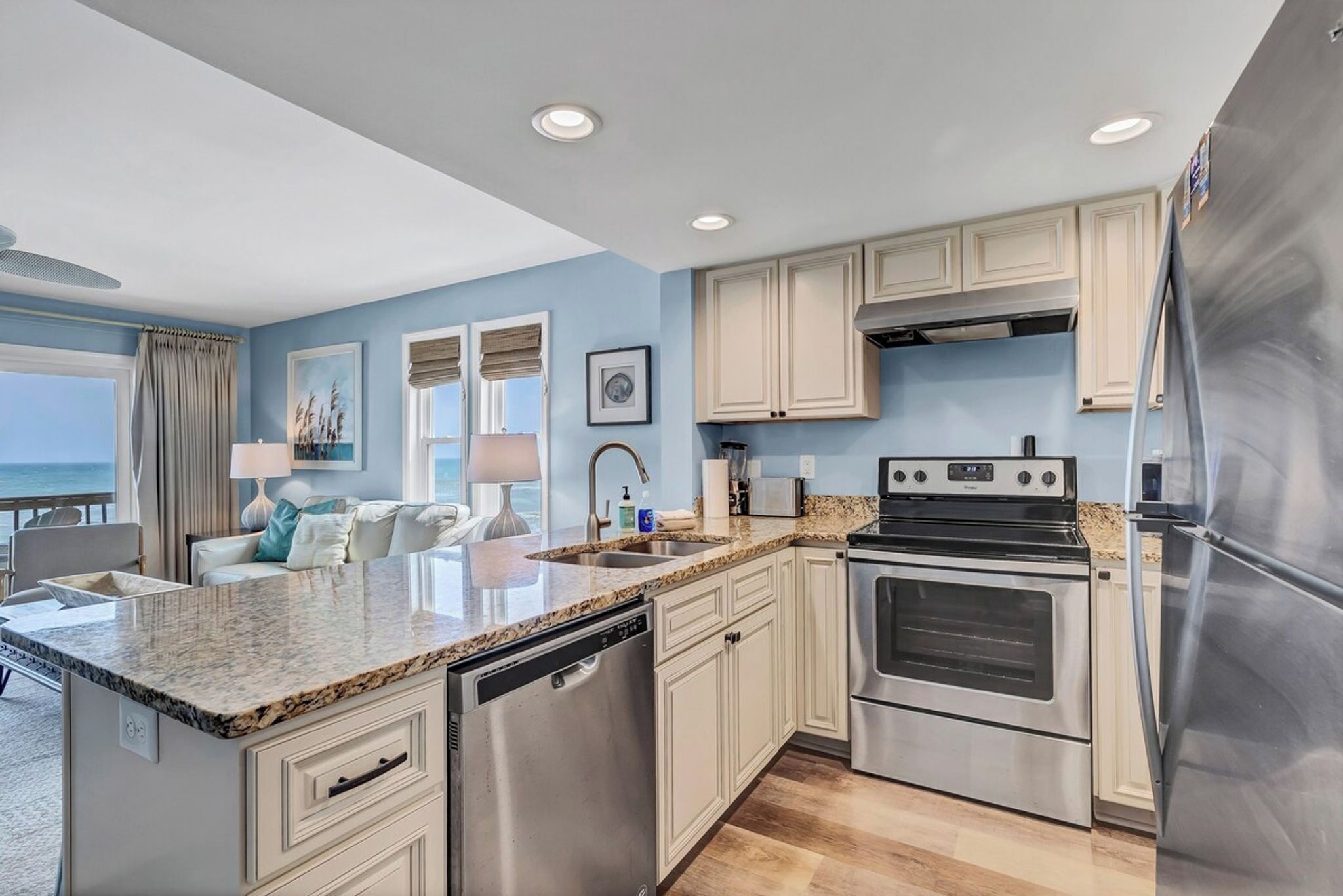 A modern kitchen with stainless steel appliances, a granite countertop, and a view of the ocean.