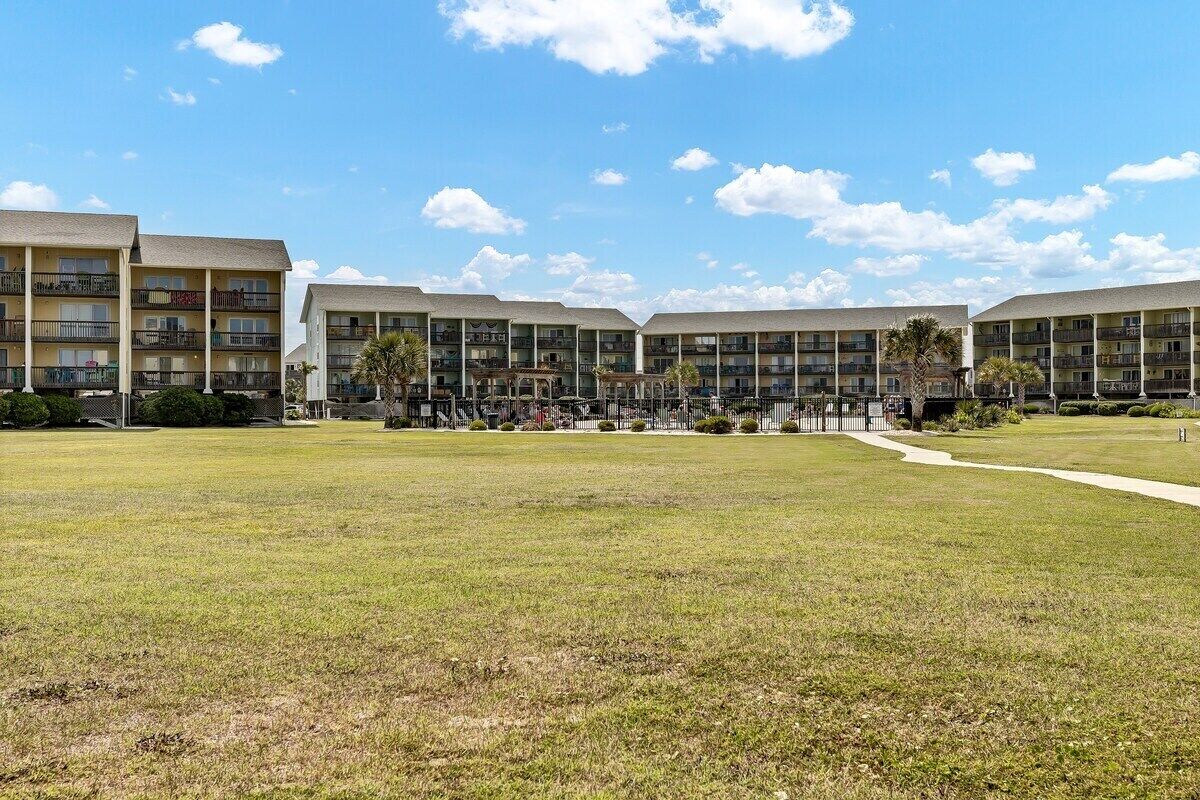 A multi-story hotel with a central courtyard, balconies, and a clear sky.