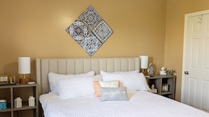A neatly made bed with white bedding, a decorative pillow with "snuggle up" text, a wall-mounted decorative tile, and a bedside table with a lamp and a small clock. - 4 Bed, 2.5 Bath, 3 KING BEDS on a Private Lake with Dock! Family Friendly (Crittenden)