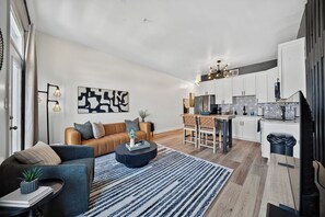 A modern living room with a sofa, coffee table, and a dining area with chairs.