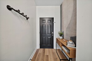 A hallway with a dark wooden door, a wooden console table with a vase and books, and a textured wall.