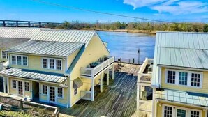 A waterfront property with two houses featuring gabled roofs and wooden decks.