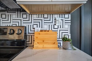 A kitchen with a modern stove, a wooden cutting board, and a potted plant.