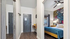 A bedroom with a bed, a desk, and a door.