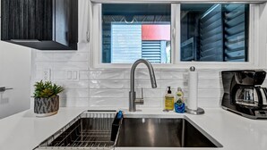 A modern kitchen with a stainless steel sink, a built-in oven, and a window with blinds. - Modern Flat - Downtown (Wilmington)