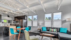 A modern living room with a sofa, chairs, a coffee table, and a dining area with a table and chairs. - Modern Flat - Downtown (Wilmington)