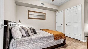 Un dormitorio con cama, ventilador de techo, puerta y espejo en la pared.