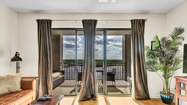 Una sala de estar moderna con un sofá, una mesa de centro y un ventanal con cortinas.