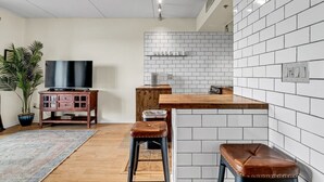 Una cocina moderna con azulejos blancos tipo metro, encimera de madera y estufa empotrada.