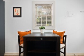 A dining table with two chairs, a potted plant, and a framed picture on the wall. - Relaxed Garden - 4 miles to Beach! (Wilmington)