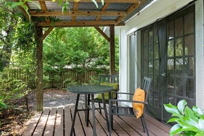 A covered patio with a table and chairs, surrounded by a wooden deck and a wooden fence. - Relaxed Garden - 4 miles to Beach! (Wilmington)