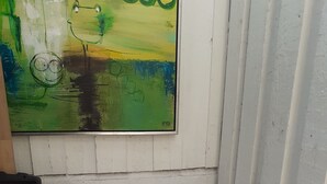 A bed with white bedding, a grey headboard, and a painting above it.
