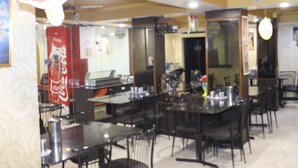 Un restaurante con varias mesas y sillas, un letrero de Coca-Cola y un espejo que refleja el interior.