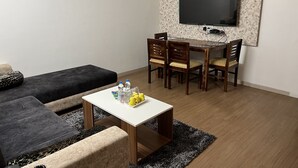 Una sala de estar con un sofá, una mesa de centro y un televisor montado en la pared.