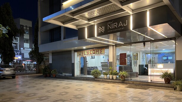 Una entrada de hotel moderna con fachada de vidrio, un mostrador de recepción y un letrero que dice 'Welcome'.