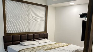 Una cama bien tendida con un cabecero, un ventilador de techo y una pared con un diseño geométrico.