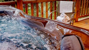 Een hottub met een houten terras en een handdoekhouder.
