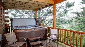 Een houten terras met een jacuzzi, een stoel en een opstapje.