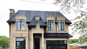 A two-story house with a stone facade, a black roof, and a garage. - Brand New Walk Out Bsmt Apt Near Beach  (Pickering)
