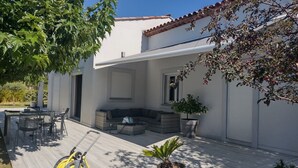 Une terrasse avec des meubles d’extérieur, un enrouleur de tuyau d’arrosage et un pot de fleurs.