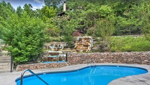 A swimming pool with a stone wall and a wooden deck. - 10 Min to Gatlinburg Strip Hot Tub King Bed Pool, 5 min to Rocky Top Sport World (Gatlinburg)