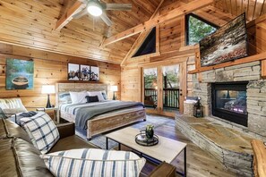 Ein gemütliches Blockhaus-Interieur mit einem großen Bett, einem Kamin und einer Steinwand.