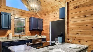 A modern kitchen with wooden walls, dark cabinets, a marble countertop, and a built-in stove. - 10 Min to Gatlinburg Strip Hot Tub King Bed Pool, 5 min to Rocky Top Sport World (Gatlinburg)