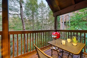 Eine Holzterrasse mit Tisch und Stühlen, einem roten Grill und einem Blumentopf.