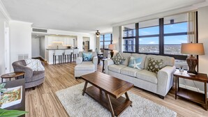 Una sala de estar moderna con un sofá, una mesa de centro y vistas de la ciudad a través de amplios ventanales.