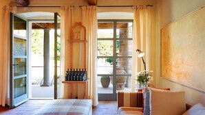 A bedroom with a bed, a chair, a table with a lamp, and a window with curtains. - Villa Noce in most Exclusive Borgo in Tuscany (Pian di Sco)