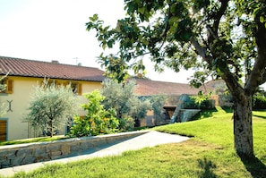 A residential property with a stone pathway, a tree-lined yard, and a house with a tiled roof. - Villa Meli in most Exclusive Borgo in Tuscany (Pian di Sco)