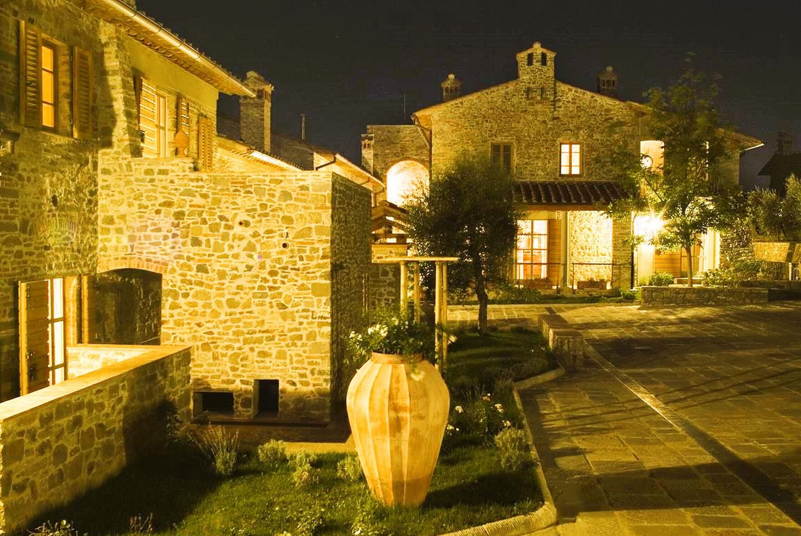 Edifici de pedra amb un pati interior, un vas gran i una entrada ben il·luminada.