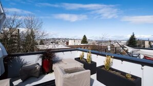 A rooftop terrace with outdoor seating, potted plants, and a view of a cityscape. - Capitol Hill Townhouse with Private Rooftop Deck — Space Needle & Skyline Views (Seattle)