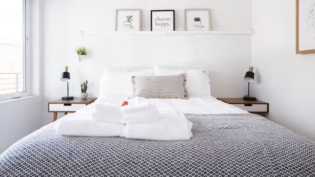 A neatly made bed with a patterned bedspread, a bedside lamp, a small potted plant, and a framed quote on the wall. - Capitol Hill Townhouse with Private Rooftop Deck — Space Needle & Skyline Views (Seattle)