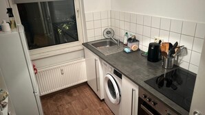 Una cucina compatta con lavatrice integrata, lavello e piano cottura.