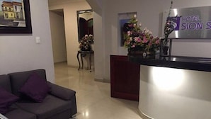A hotel reception area with a reception desk, a sofa, and a chair. - Hotel Casa Morada (Bogotá)