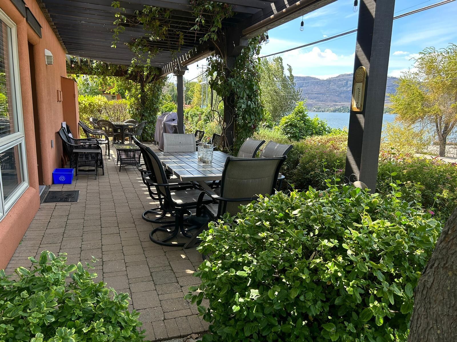 An outdoor patio with a table and chairs, a grill, and a view of a lake.
