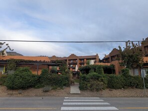 A residential area with multiple-story buildings, a pedestrian crossing, and a mountain in the background. - Stunning Lakeside Villa (Osoyoos)
