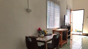 Ein Essbereich mit Tisch, Stühlen und einem Fenster mit Jalousien.