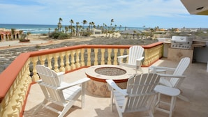 A patio with white Adirondack chairs, a circular fire pit, and a grill. - "I have traveled the world and this is the best beach I have ever seen" (La Ribera)