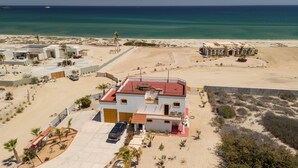 A coastal property with a large building, a parking area, and a beach view. - "I have traveled the world and this is the best beach I have ever seen" (La Ribera)