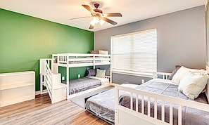 A bunk bed room with a ceiling fan, a window with blinds, and a green wall.