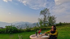 A dining table with a view of mountains in the background. - Haut Monde King's Paradise Resort  (Tehri)