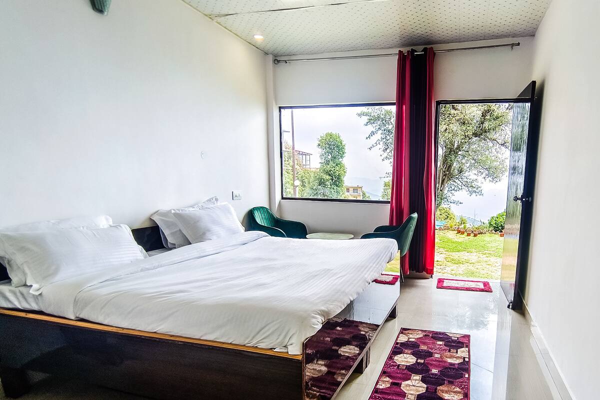 Habitació d'hotel moderna amb un llit gran, una taula petita i vistes a l'exterior.