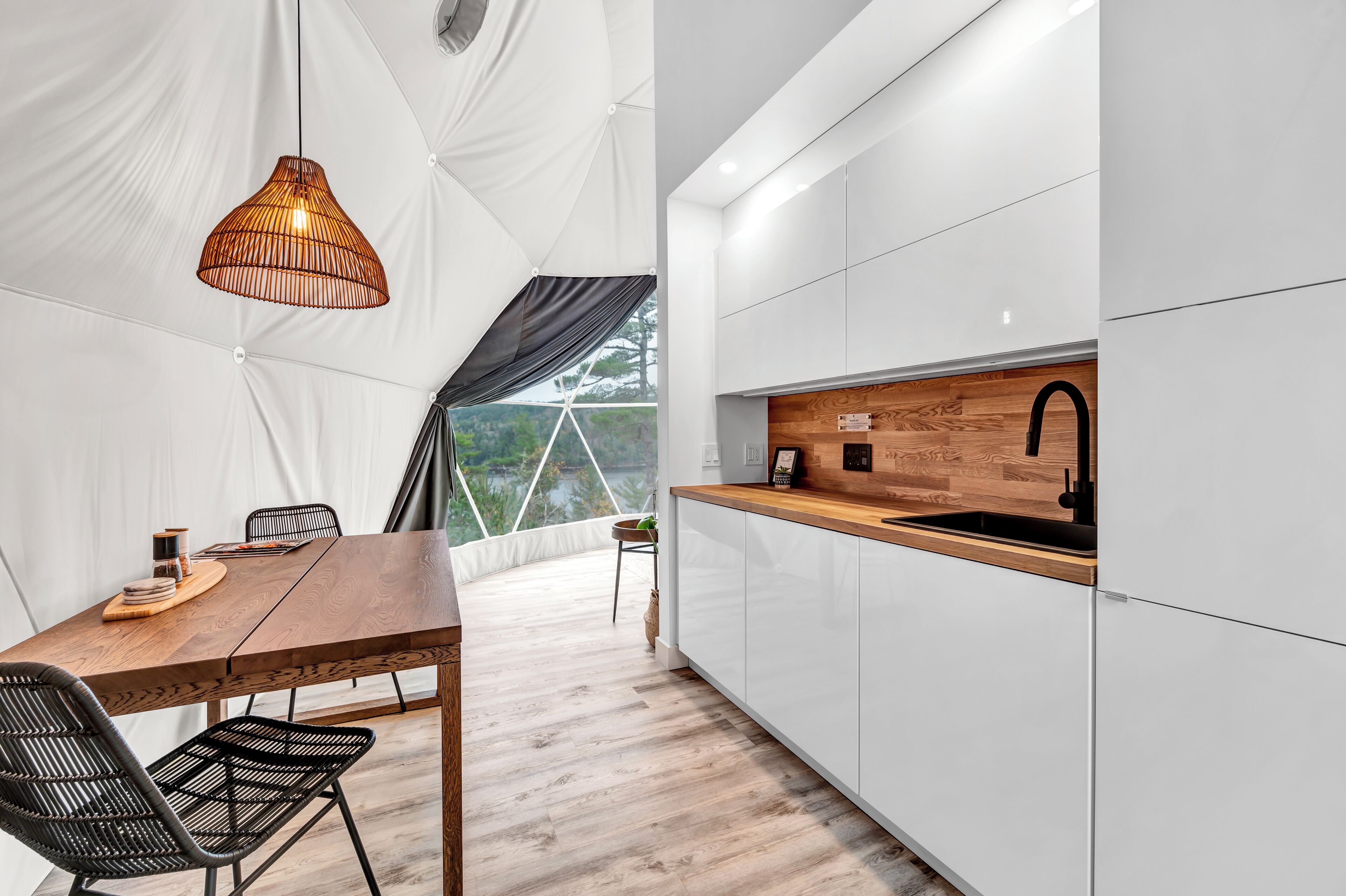 A modern kitchen with a wooden countertop, white cabinets, and a hanging light fixture.