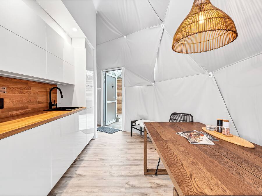 A modern kitchen with white cabinetry, a wooden countertop, and a hanging light fixture.