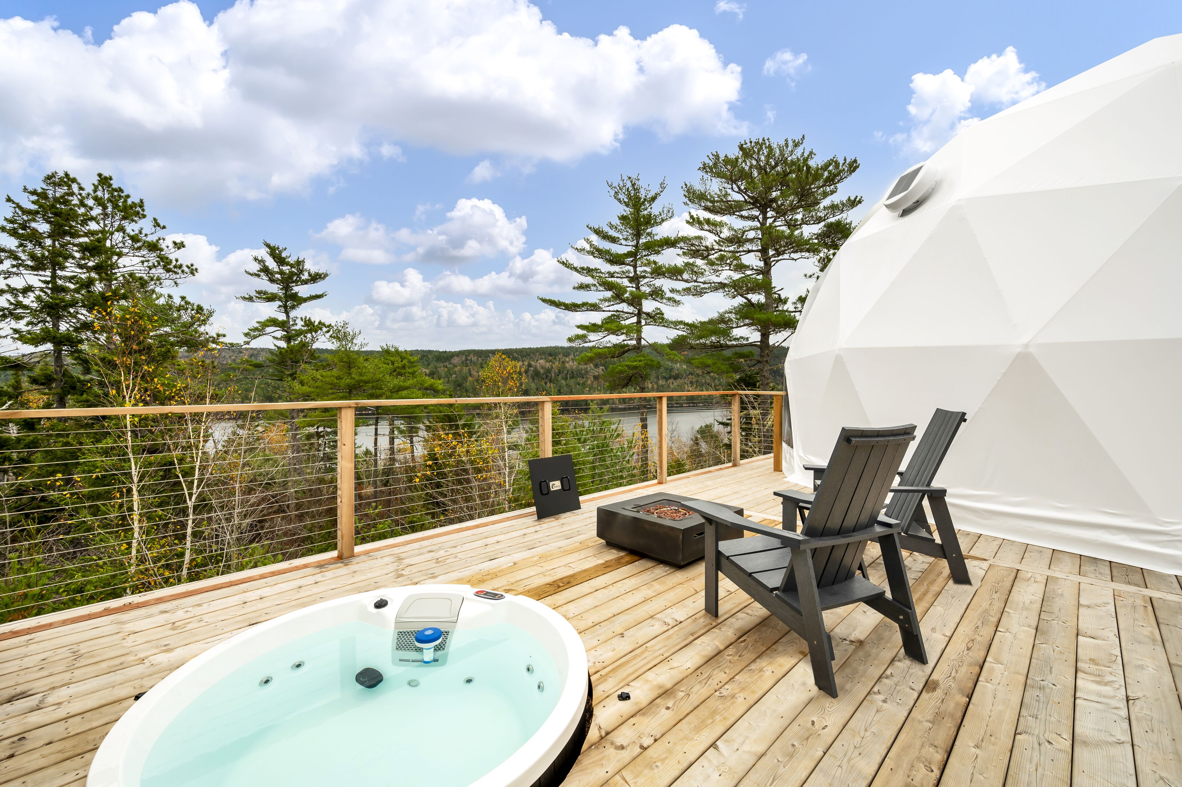 A wooden deck with a hot tub, chairs, and a white dome structure.
