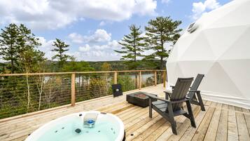 A wooden deck with a hot tub, chairs, and a white dome structure.