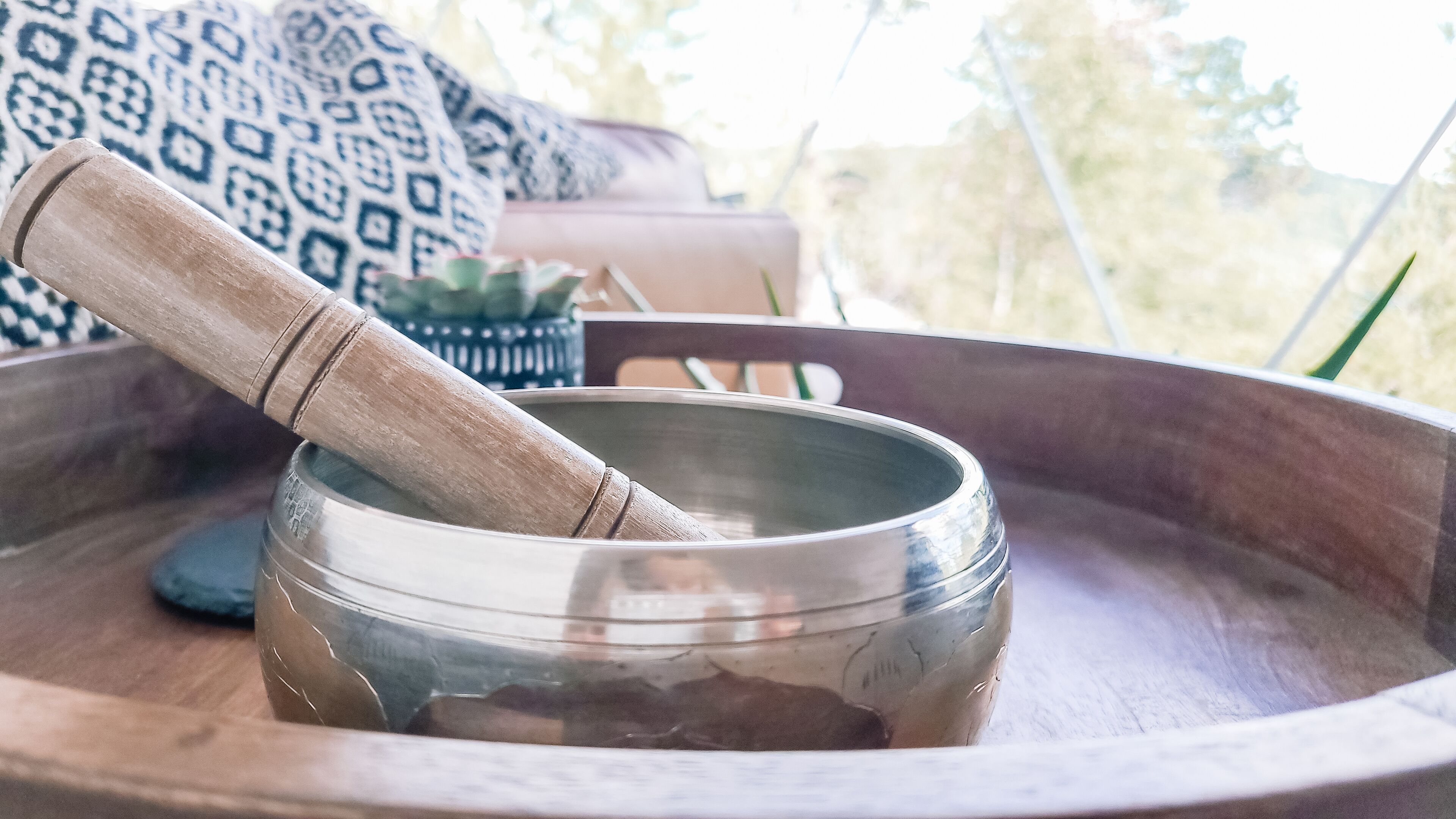 A wooden bowl with a mallet on a tray.